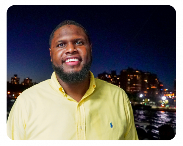 Chris smiles into camea wearing a yellow button down polo shirt.