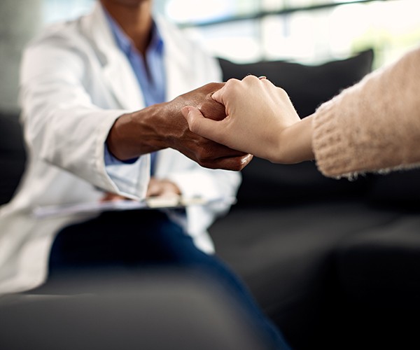 Closeup of psychotherapy session, therapist holds patient's hand. Image by Drazen Zigic on Freepik