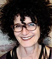 Nancy Gershman smiles wearing dark rimmed eyewear and curly dark hair