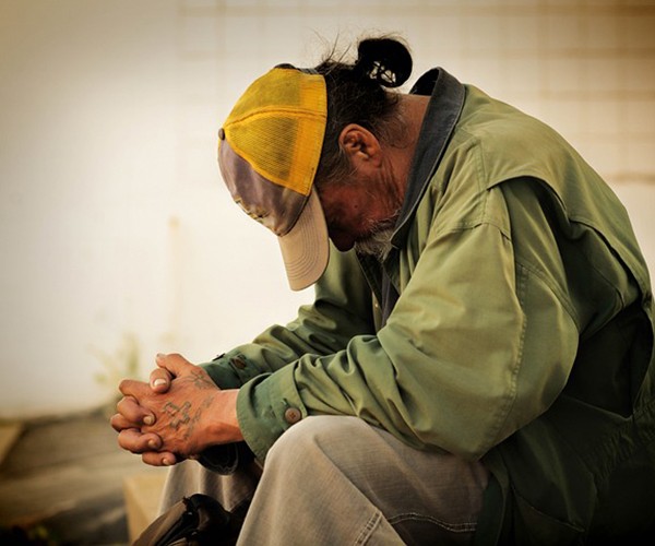 A man sits, dejected with his head down