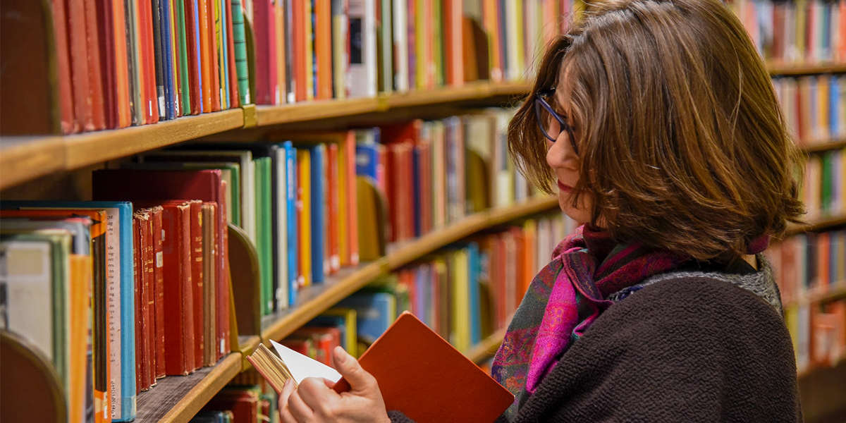 Woman standing in library looking inside of book