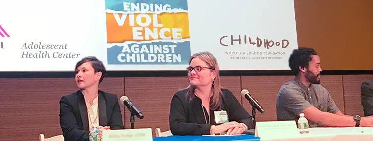 Yamile Marti is seated at a panel between two individuals wearing a dark top/blazer and eyeglasses.