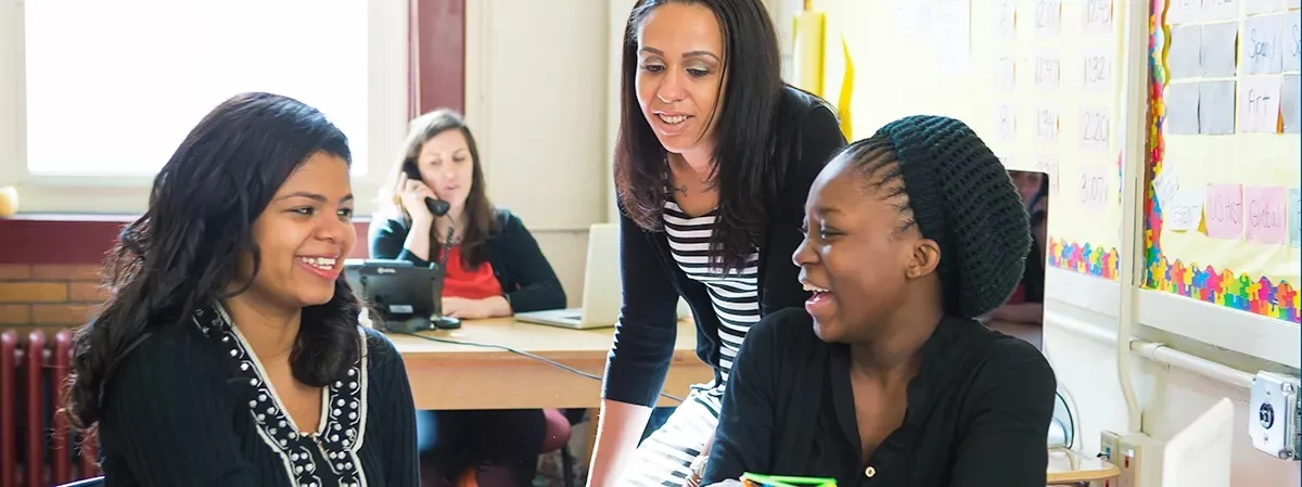 MSW student in practicum placement helps two high school students with a class activity.