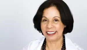 Dr. Cabrera smiles into camear wearing a dark blouse and white blazer.