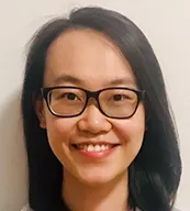 Qin Sun wears dark rimmed eyeglasses and smiles into camera lens. 