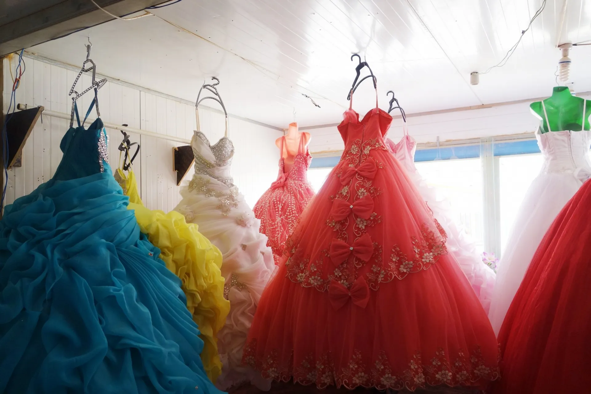 Beautiful wedding gowns in various colors of blue, yellow, white, fuschia are on display at a Syrian bridal shop. 