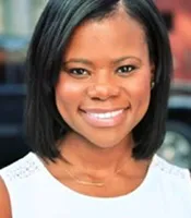 Ashleigh wears a side part of hair and a white round neck top