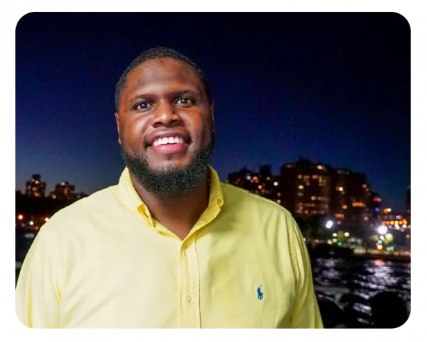 Chris smiles into camea wearing a yellow button down polo shirt.  