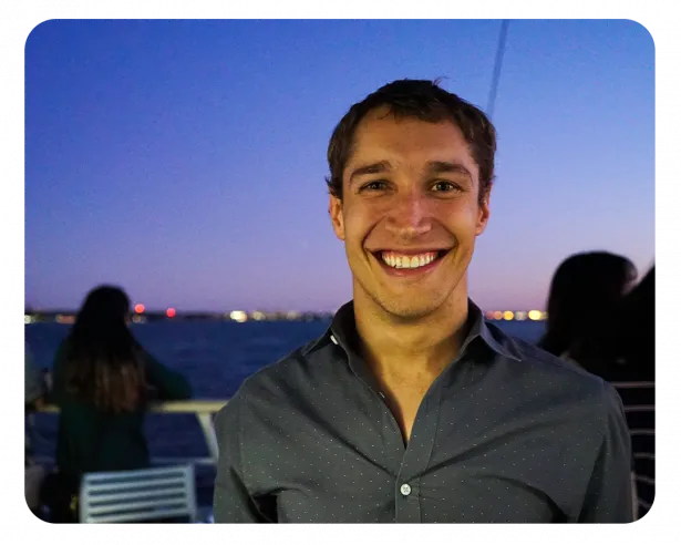 Diego smiles wearing a charcoal grey button down collared shirt. 