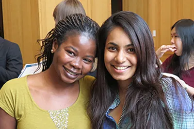 Two women stand close together with arms around each other.
