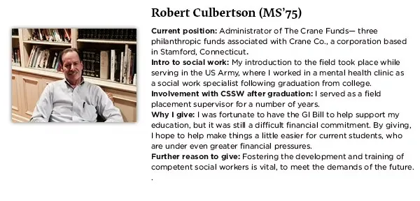 Robert wears a button down light grey shirt and is seated in front of a library shelf.