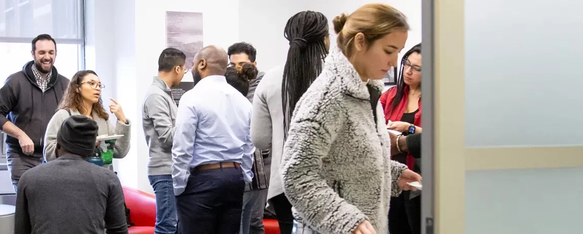 various people are in conversations within a room while a few are standing several are seated in discussion.