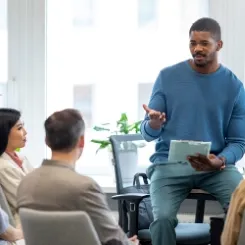 Man sitting down and speaking with colleagues 