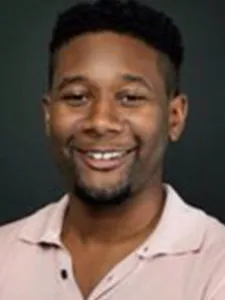 James wears a smile and a champagne colored button down shirt.