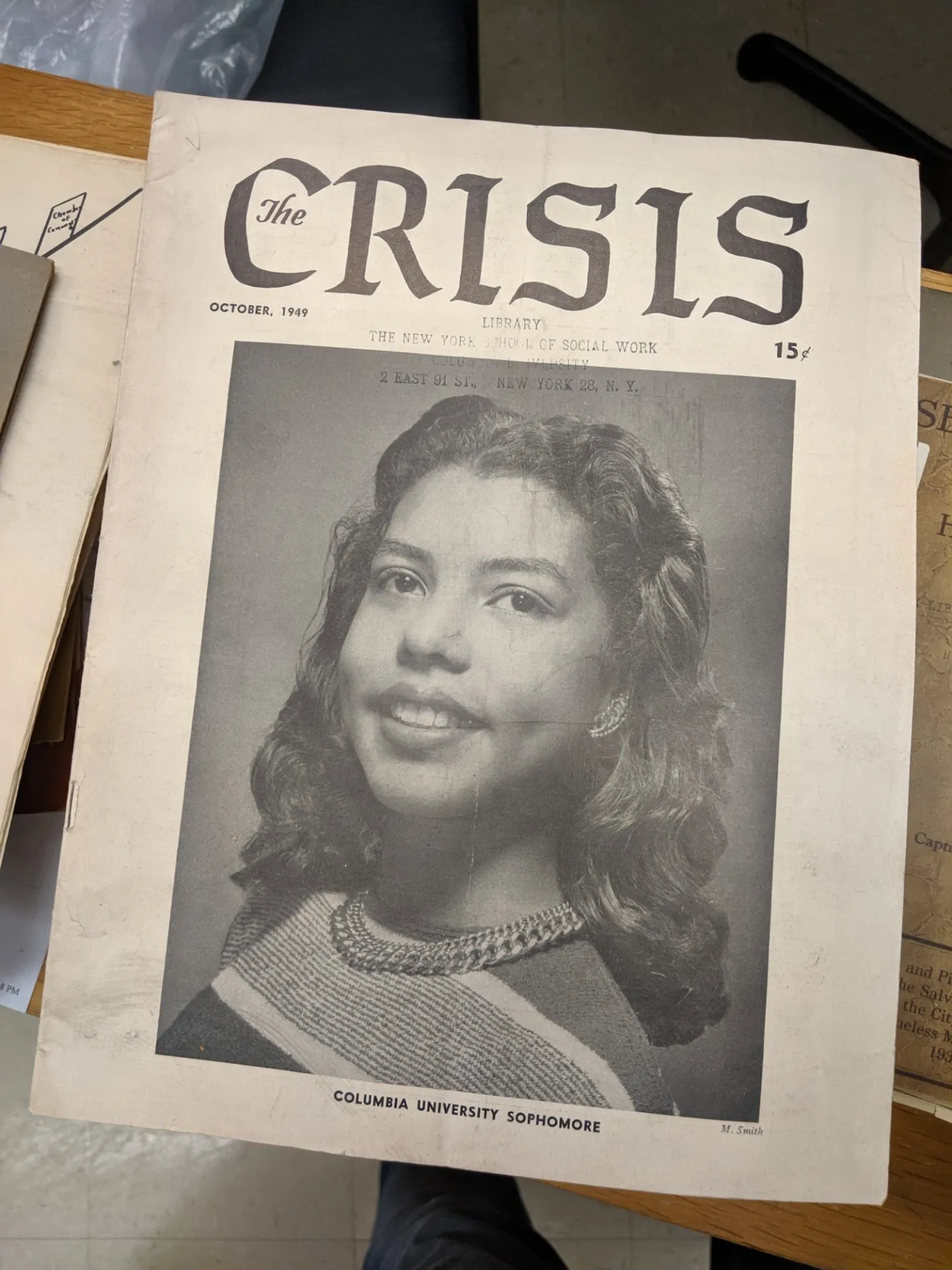 Front cover page to Crisis detailing a woman smiling wearing a multi striped blouse and gold necklace