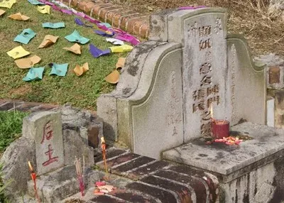 tombstoe at gravesite adorned with candles and incense