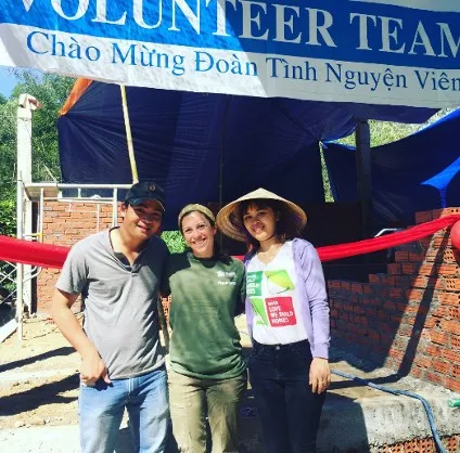 A Vietnamese friend wearing a cap, grey shirt and jeans pose with Gina wearing a green tshirt and jeans along with another social worker student wearing a non la, t shirt, lavendar sweater and black pants 