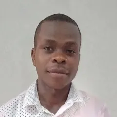 Zakayo faces the camera slight smile wearing a colored white button down shirt with collar and polka dots.